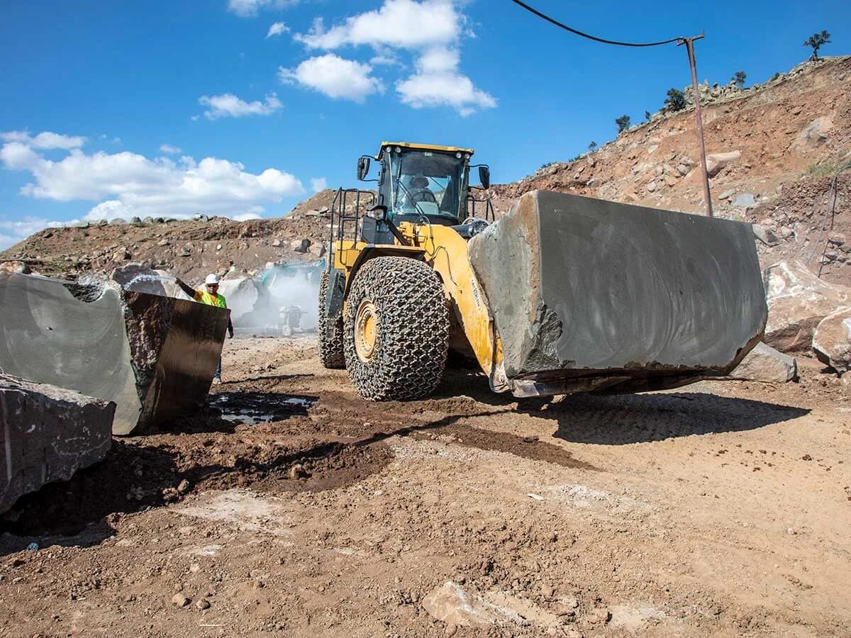 Wheel loader handling a basalt block in the quarry yard